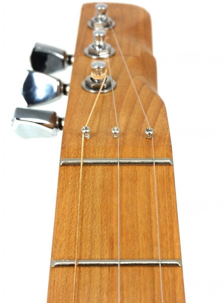 Here is another angle of a zero fret installed on a cigar box guitar. This particular guitar featured an angled headstock, so the retainer screws are just holding the strings in the correct position, not holding them down to increase break angle.